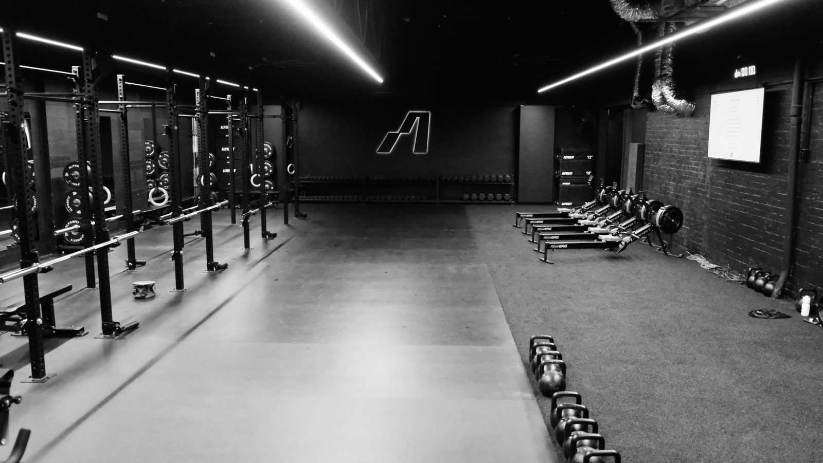 The Assembly training floor: racks, rowers and kettlebells under the lit A logo